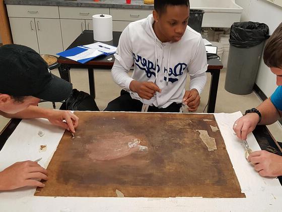 Students work on fitting the inserts and filling in the gaps with canvas fluff to even out the surface before relining.