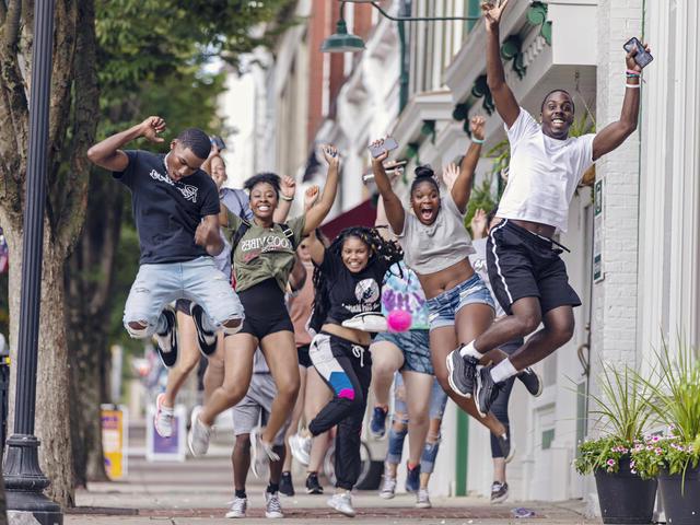 学生们在威斯敏斯特市中心的人行道上跳向空中. 