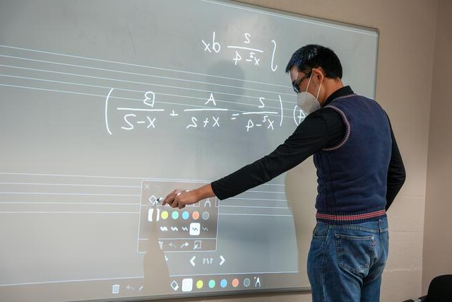 A student writes equations on a whiteboard.
