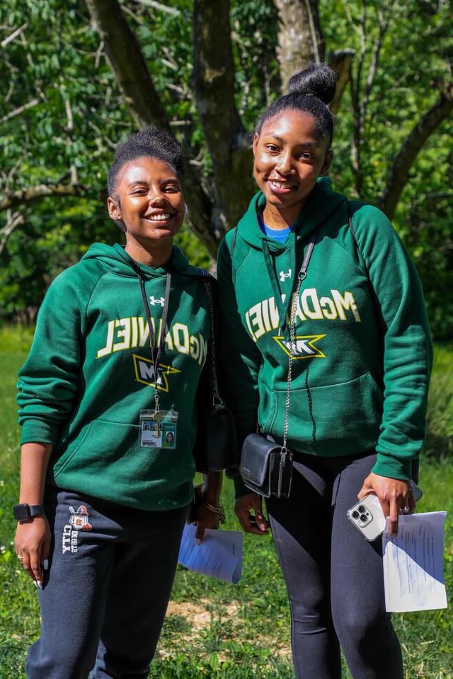 两个学生穿着绿色的金沙js6038运动衫摆姿势.